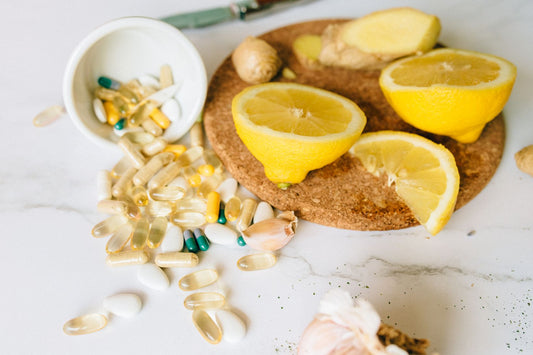 Supplement capsules beside fresh citrus fruit on a light table